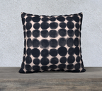 Decorative pillow with black dot pattern on a neutral background