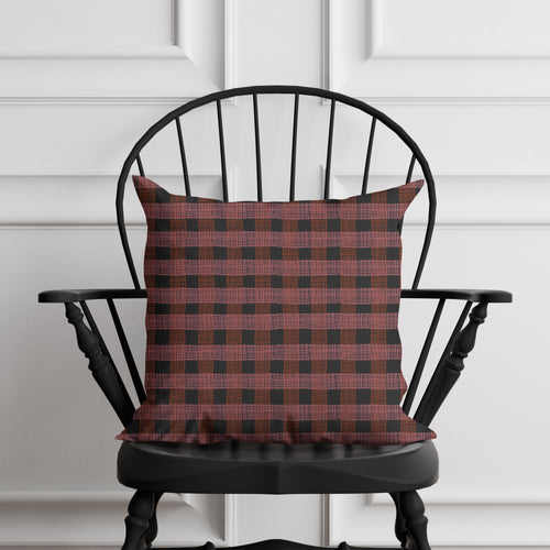 Red and black checkered pillow on a black chair against a white paneled wall.
