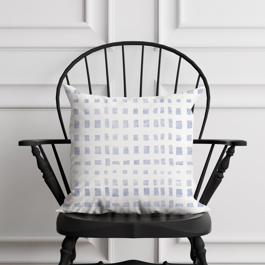 Decorative pillow with a blue and white pattern on a black chair against a white paneled wall.