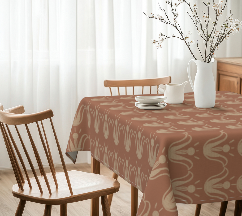 Dining table with a patterned tablecloth, chairs, and decorative items in a bright room.