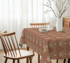 Dining table with a patterned tablecloth, chairs, and decorative items in a bright room.