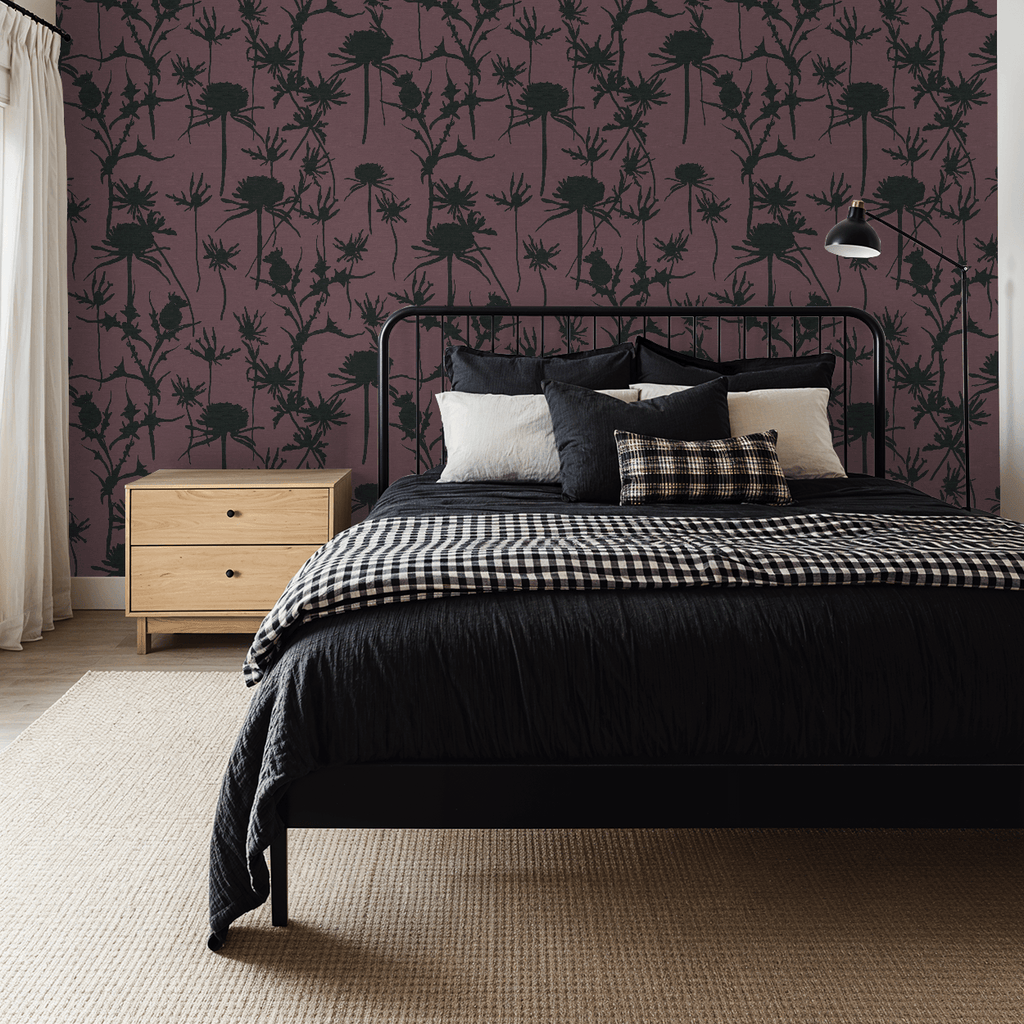 Bedroom with floral wallpaper, bed with checkered blanket and pillows, and wooden nightstand.